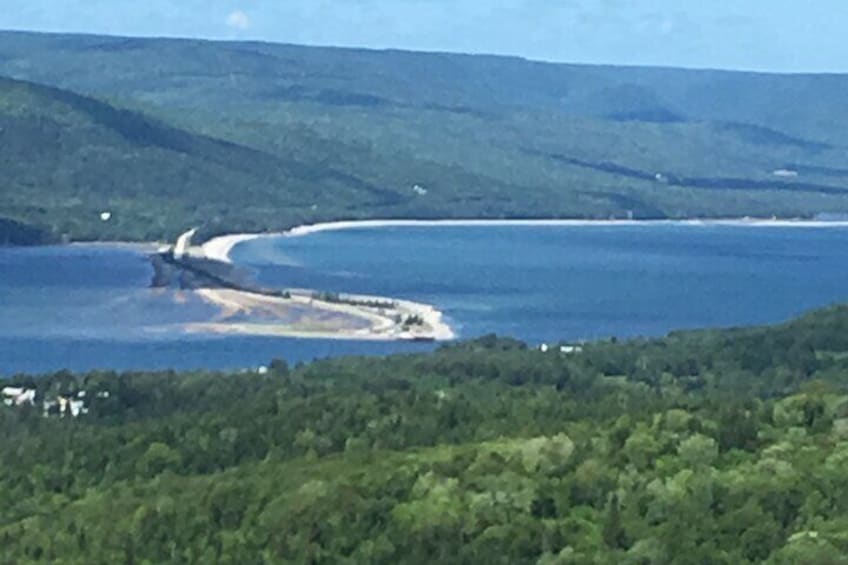 A coastal landscape with a beach, a road curving along the shore, and a forested area in the foreground. 1
