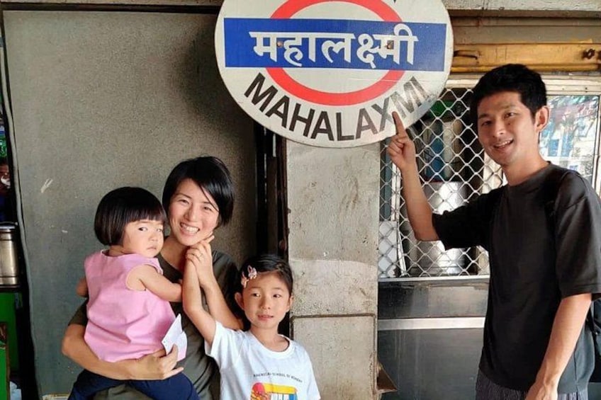 A family posing in front of a sign with 'MAHALAXMI' written on it. 3