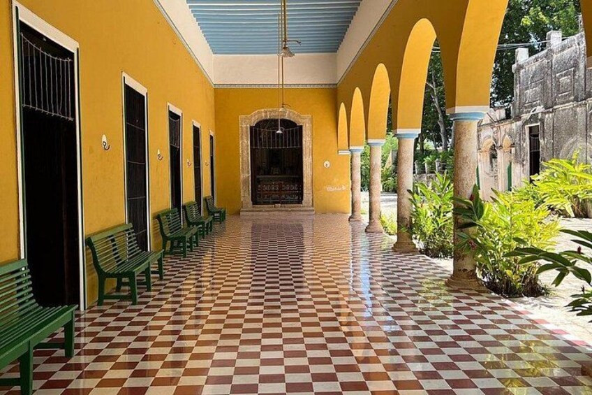 A corridor with checkered flooring, green benches, and yellow walls. 5