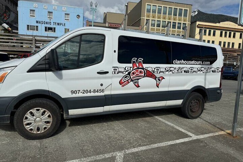 A white van parked in a lot with a tribal design and a phone number on the side. 4