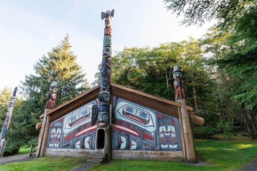 A totem pole with a painted exterior, set in a forested area. 1