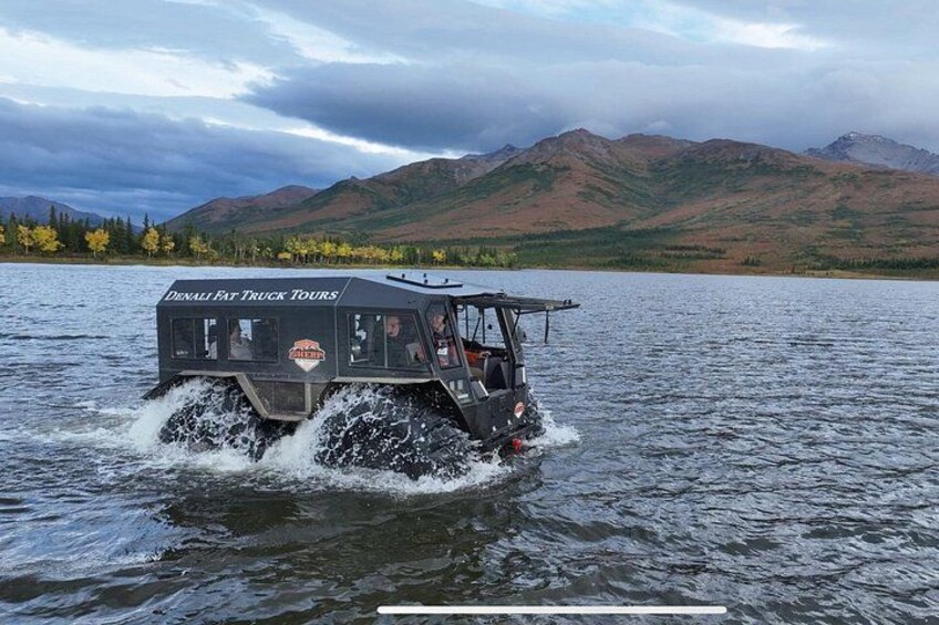 Un véhicule sur l’eau, avec des montagnes en arrière-plan. 1