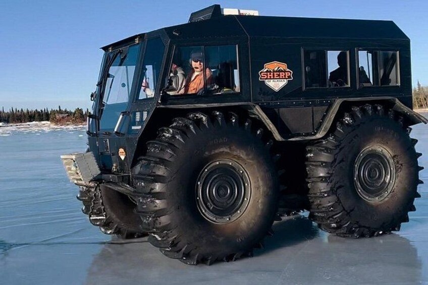 Un grand véhicule noir, orné du logo « SHERP » sur le côté, circule sur une surface gelée. 4