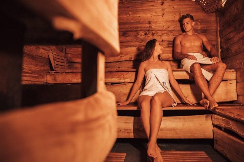 A sauna with wooden benches and a person sitting on one of them. 2
