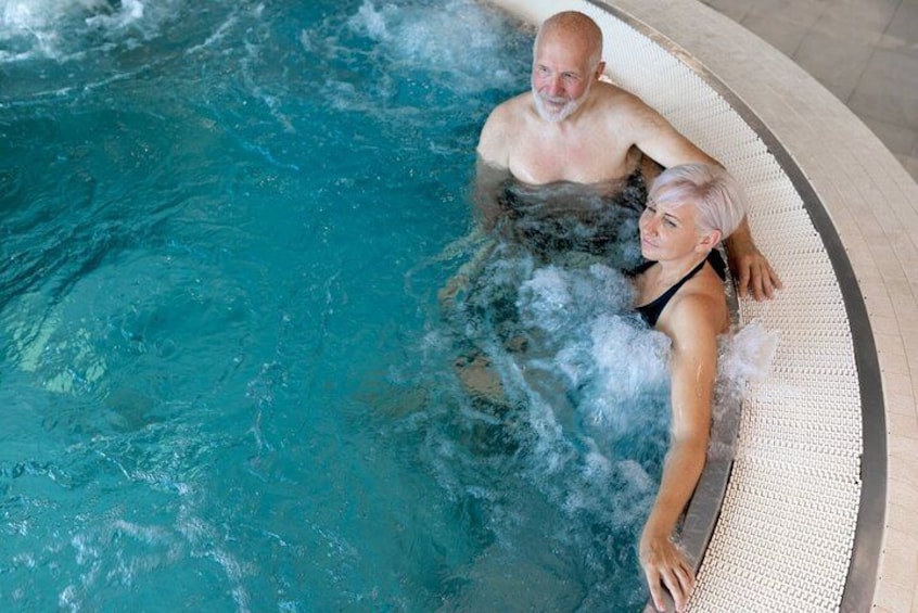 A couple in a hot tub with a tiled floor and a curved edge. 5