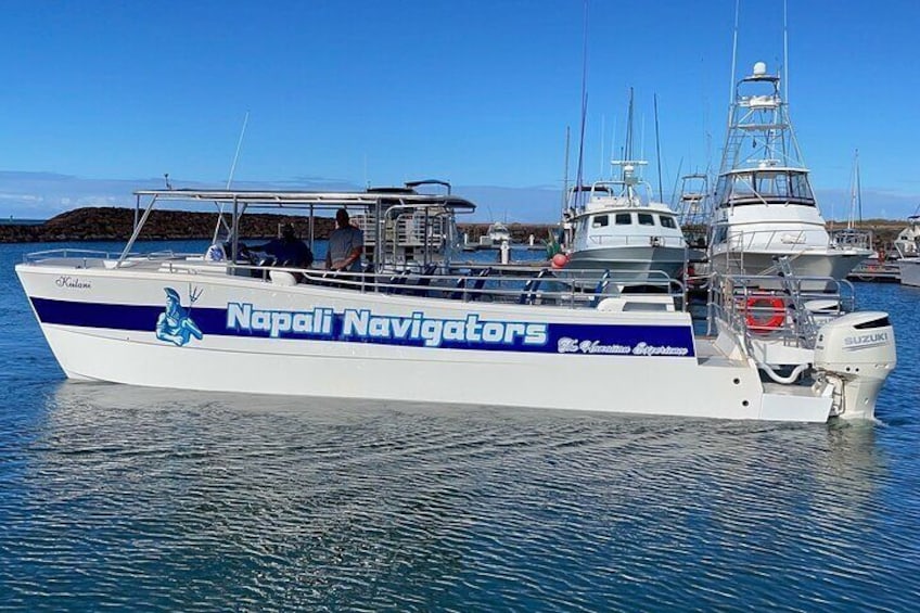 A boat named 'Napali Navigators' docked at a marina with other boats and a clear sky in the background. 4