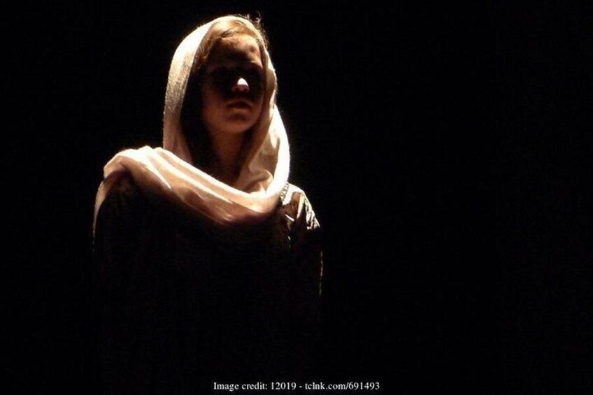 A person in a dark setting with a light-colored scarf. 4