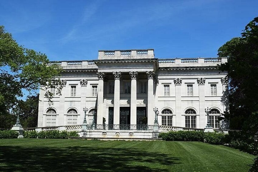 A large, classical building with columns and arched windows, surrounded by a well-manicured lawn and trees. 5