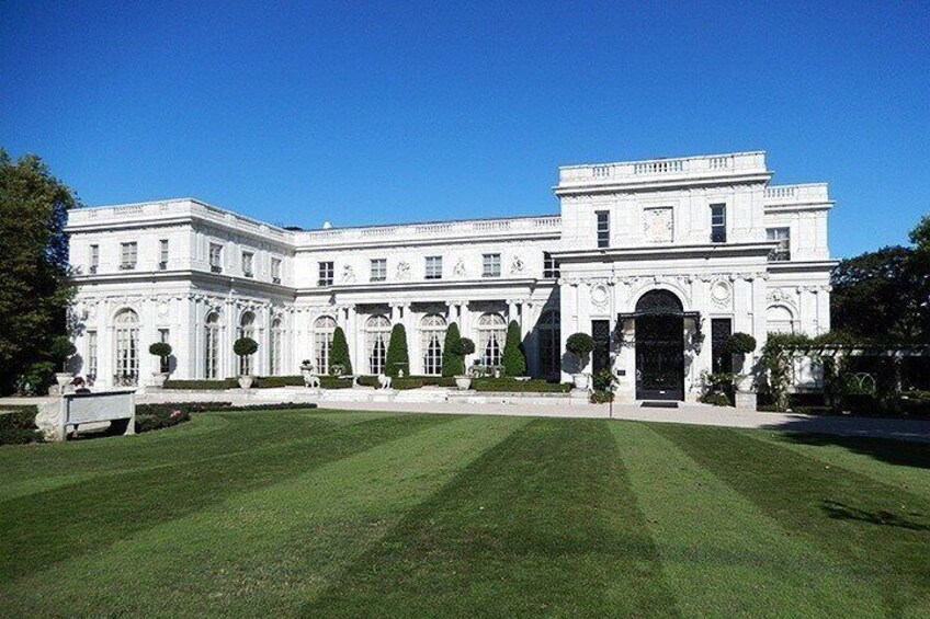 A large white building with a symmetrical facade, surrounded by a well-manicured lawn and trimmed hedges. 5