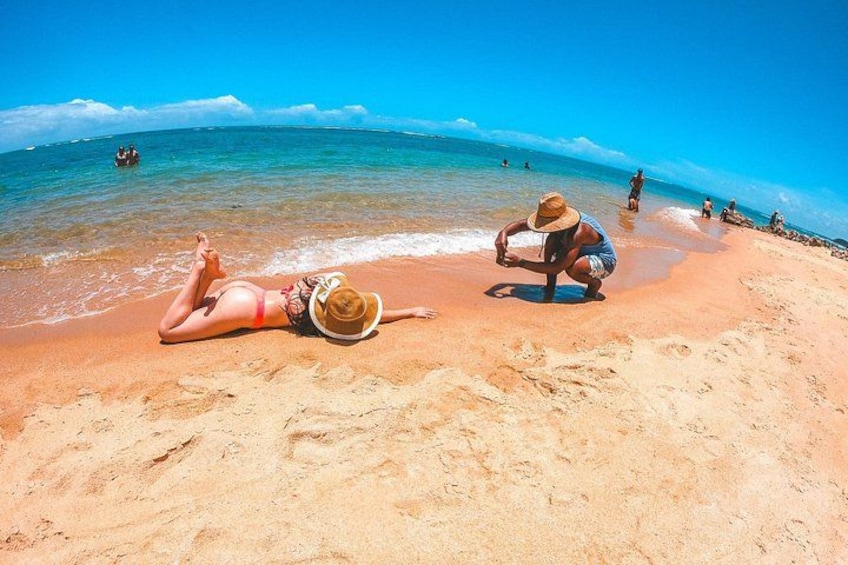 A beach with people sunbathing and a person squatting on the sand. 2