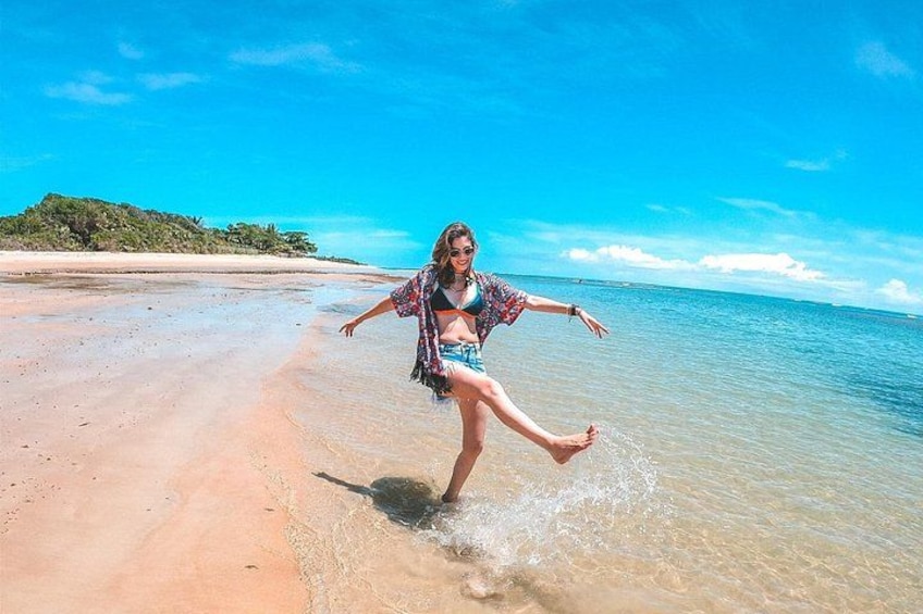 A person standing on a beach with clear water and a distant shoreline. 1