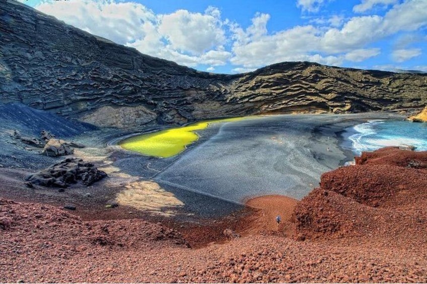 A volcanic landscape with a lava field, a yellow pond, and a beach. 4