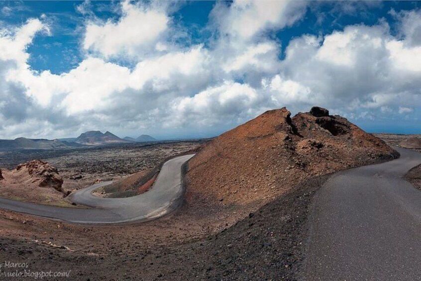 A winding road through a barren landscape with rocky hills and a clear sky. 2