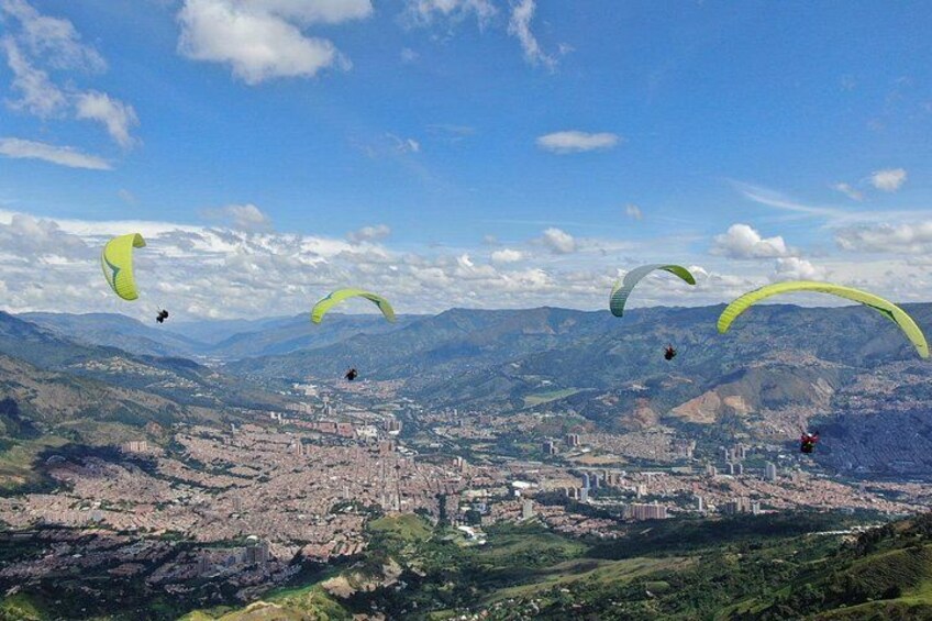 Paragliders flying over a city with mountains in the background. 1