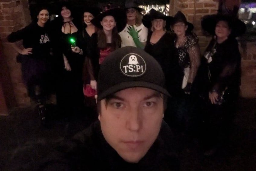 A group of people in a dark setting, some wearing hats and one with a visible T-shirt logo. 5