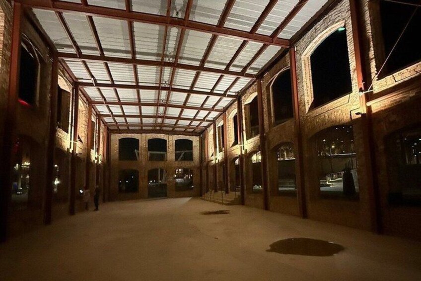 An indoor space with a high ceiling, large windows, and a concrete floor. 3