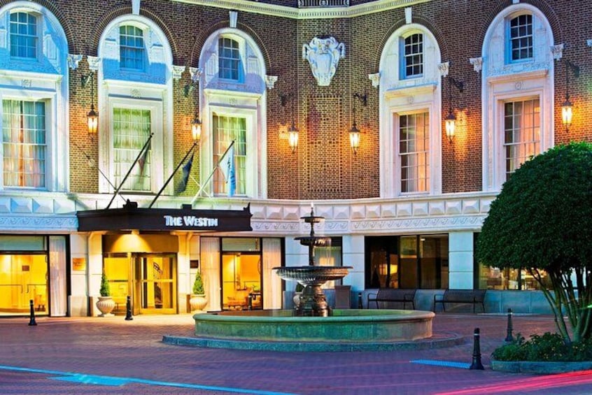 A historic building with arched windows and a fountain in front. 1