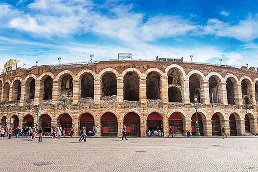 A historic building with multiple arches and a paved plaza. 1
