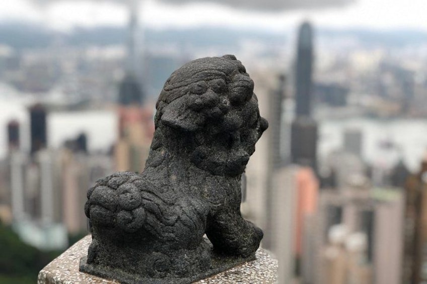 En stenløve statue på en sokkel med en byudsigt i baggrunden. 3