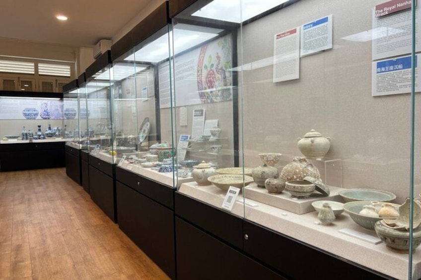 Een museumpresentatie met glazen vitrines waarin keramische objecten liggen tentoongesteld. 1