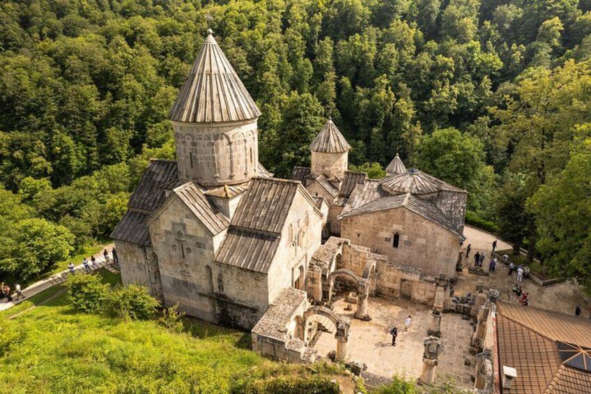 A historical stone building with a tower, surrounded by lush green forest. 2