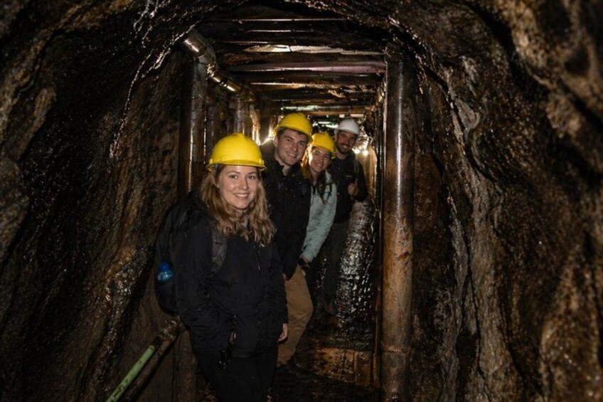 Personas en un túnel con paredes rocosas y tuberías metálicas. 4