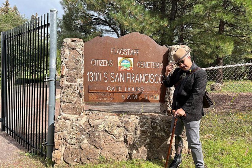 Un letrero de piedra, una reja metálica y una persona con un bastón. 1