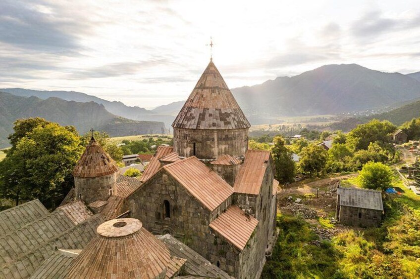 A historic church with multiple domes, surrounded by lush greenery and mountains in the background. 2