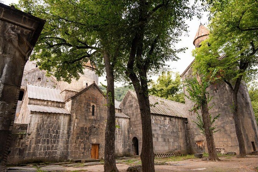 A historic stone building with a bell tower, surrounded by trees. 3