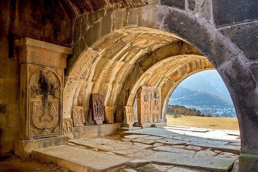 An ancient stone archway with intricate carvings and a view of a mountainous landscape. 5
