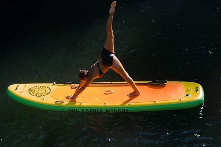 A person performing a yoga pose on a paddleboard in the water. 2