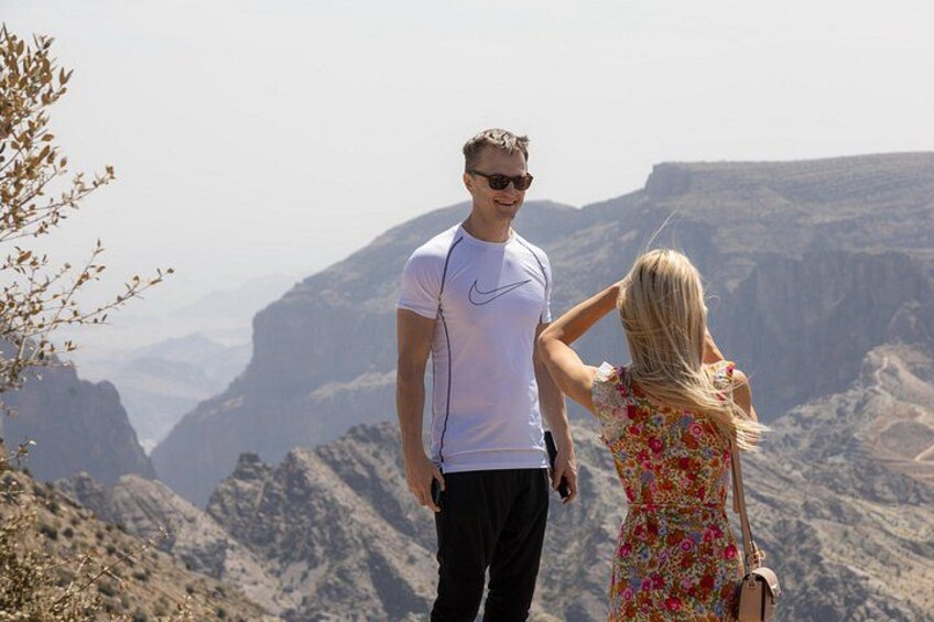 A couple standing on a mountain overlooking a canyon. 4