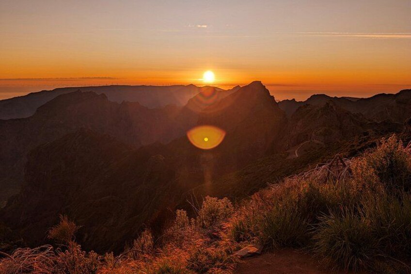 A mountain landscape at sunset with the sun setting behind the peaks. 2