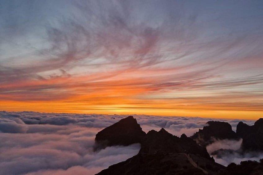 A mountain range with a sunset sky and clouds below. 3