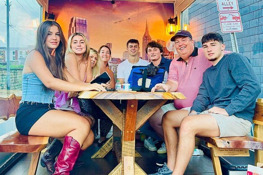 Un gruppo di persone sedute a un tavolo all'aperto con uno skyline urbano sullo sfondo. 2
