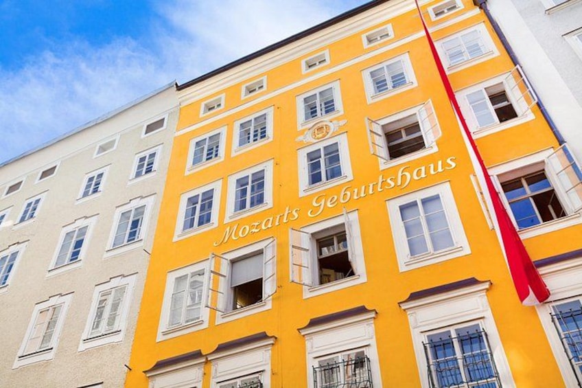 En bygning med gule og hvide facader, mange vinduer og et rødt flag. 3