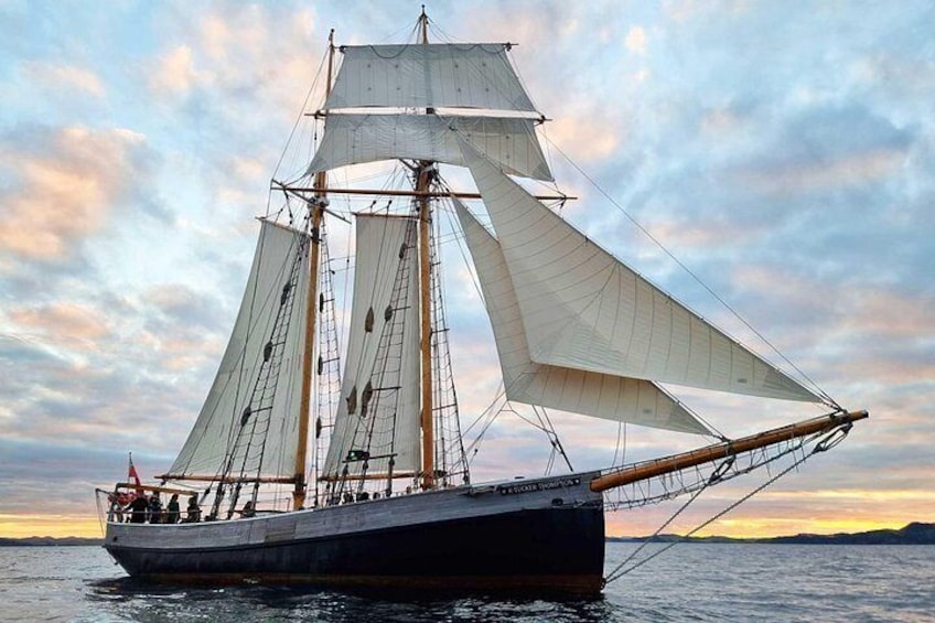 A sailing ship with multiple sails, a wooden hull, and a crew on deck. 1