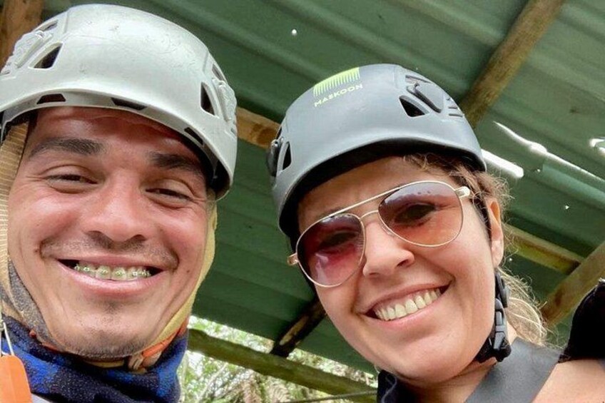 Two people wearing helmets, one with a visible logo, and a metal structure in the background. 5