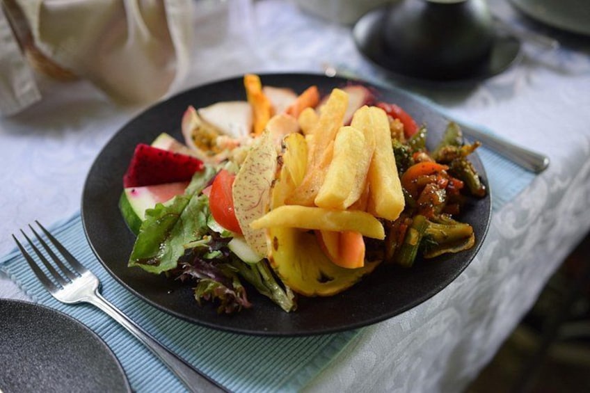 A plate of food with a salad, fries, and vegetables. 4