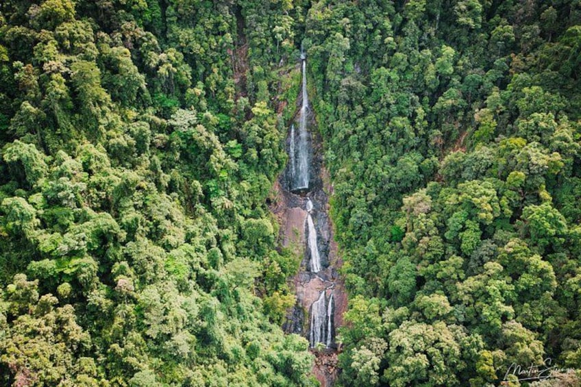 A waterfall cascading down a steep cliff surrounded by dense green forest. 5