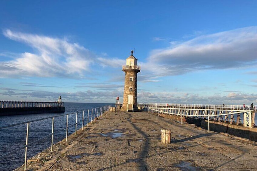A lighthouse on a rocky pier with a clear sky. 1