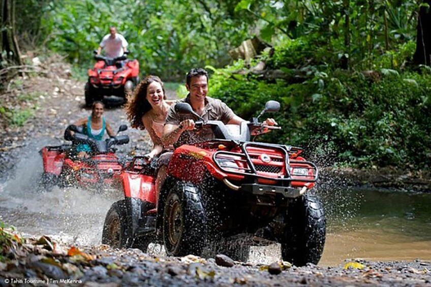 People riding ATVs on a muddy path with water splashing around. 4