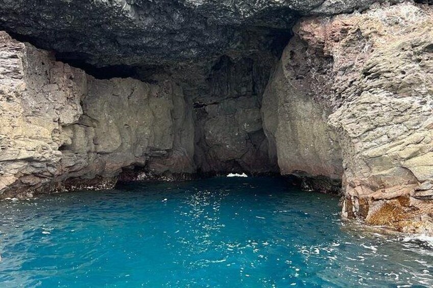 A natural rock formation with a clear blue pool at its base. 3