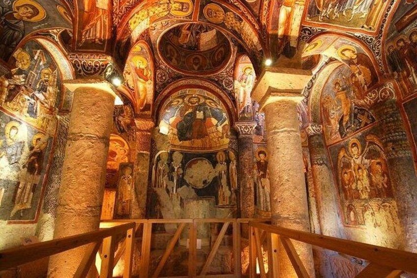 Een kerkinterieur met versierde zuilen, gedetailleerde fresco's en een houten balustrade. 1