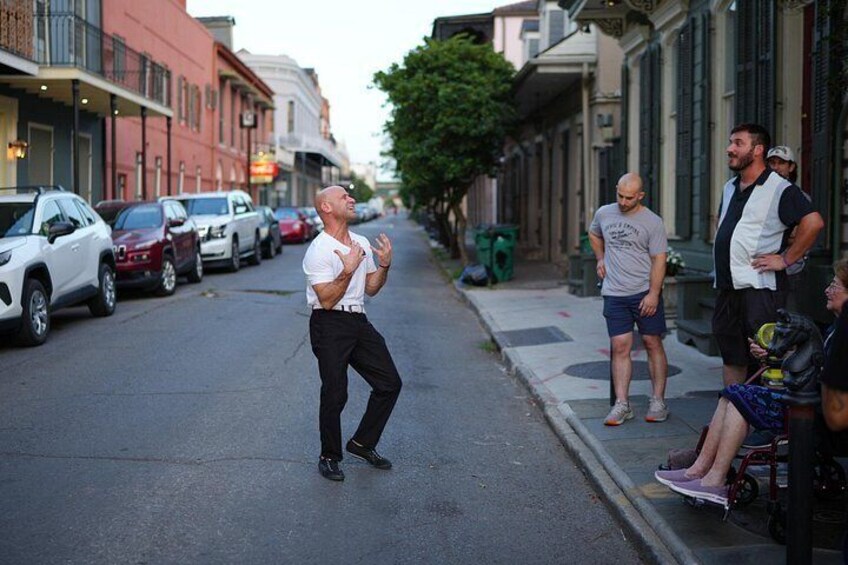Un homme qui danse dans une rue, avec des voitures garées et des immeubles en arrière-plan. 4