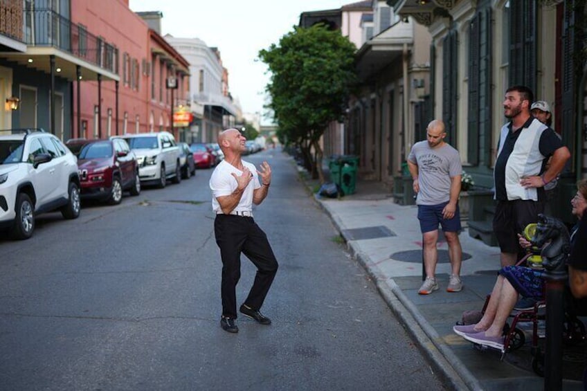 A man dancing on a street with parked cars and buildings. 3