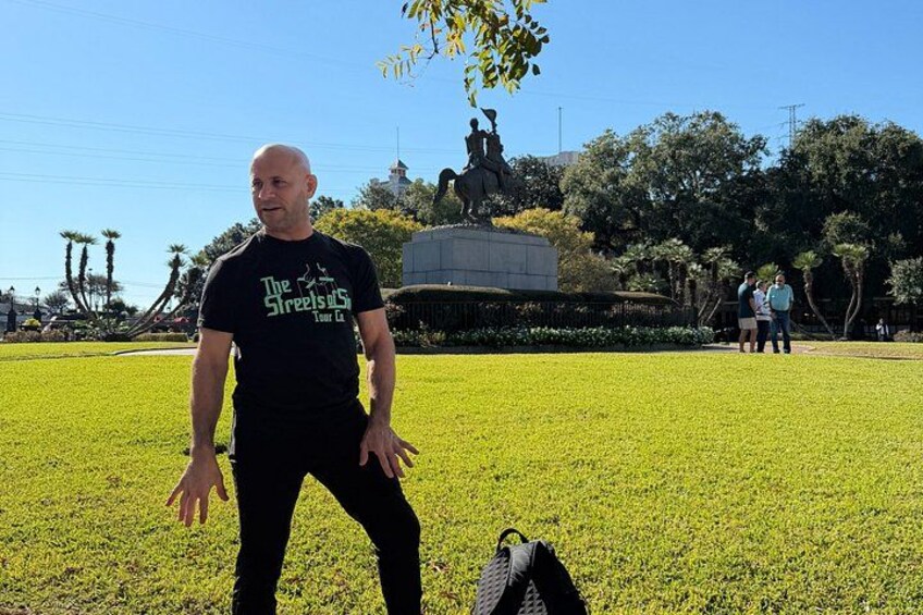 A person standing in a park with a statue in the background. 2
