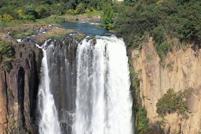 Un'imponente cascata si getta da una ripida scogliera, circondata da vegetazione lussureggiante. 3