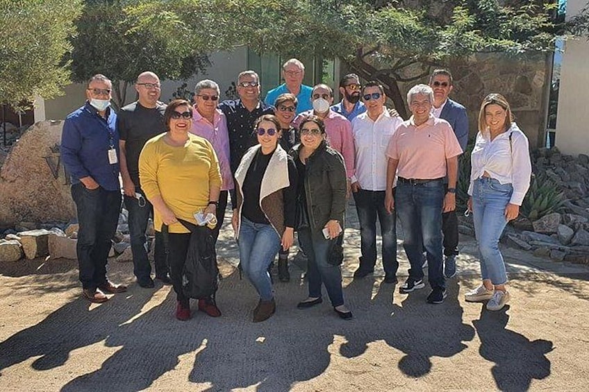 A group of people standing outdoors with a rocky background and trees. 3