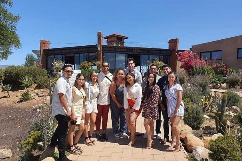 A group of people posing in front of a building with a garden. 1